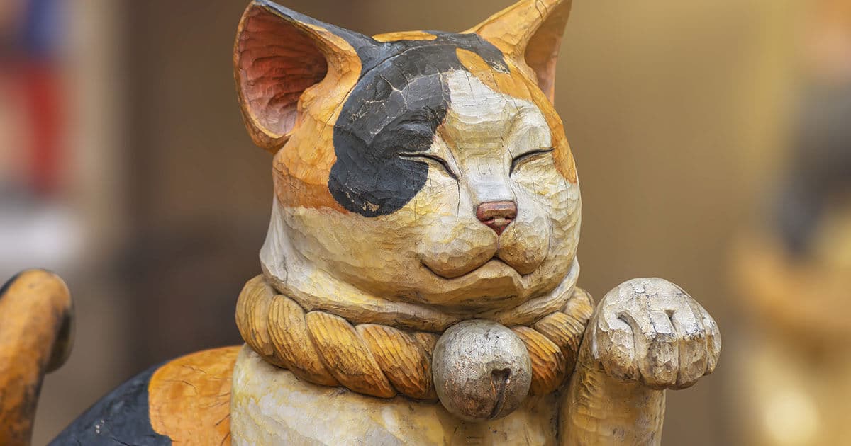 Primer plano de una escultura de madera que representa el maneki-neko.