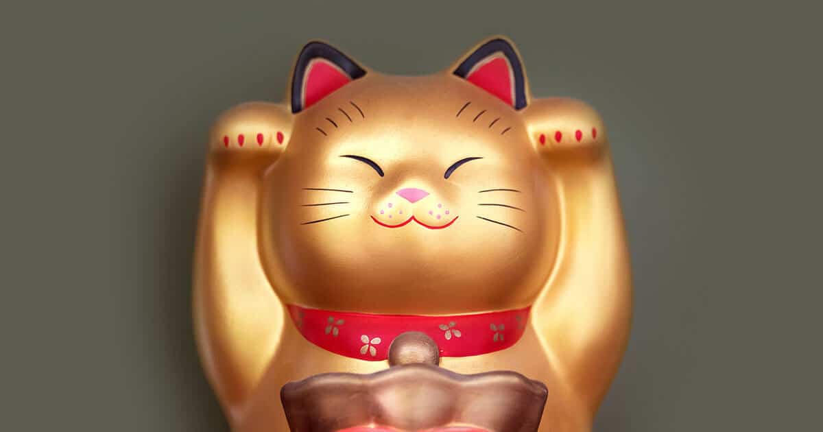Maneki Neko con las patas levantadas y un saco de dinero