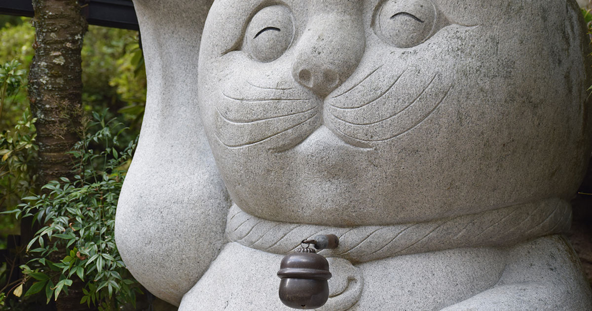 Estatua de un Maneki Neko con un "Rin" campana en el cuello